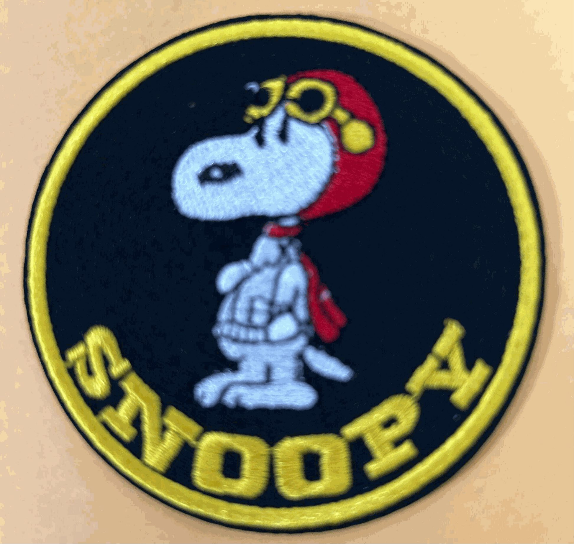 Snoopy Red Baron patch featuring Snoopy in red pilot helmet and goggles on black circular background with yellow border and text.