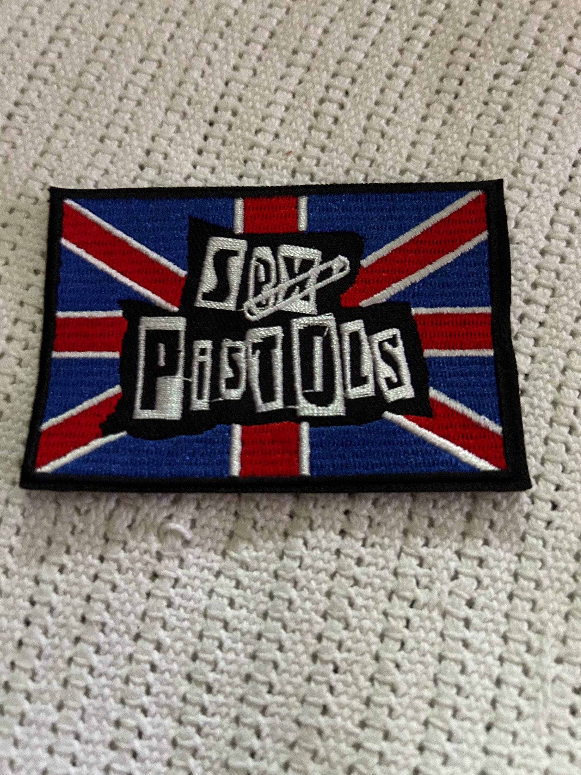 S*x Pistols patch with bold white text on a blue and red Union Jack background, embroidered and iron-on backing