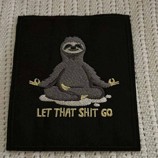 Black patch with embroidered meditating sloth and "LET THAT SHIT GO" text in beige