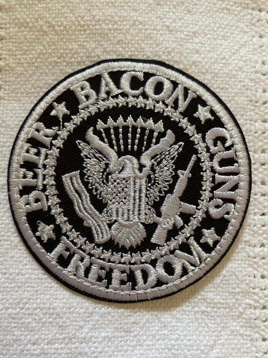 Round embroidered patch featuring an eagle and the slogan beer bacon guns freedom in bold white on black background