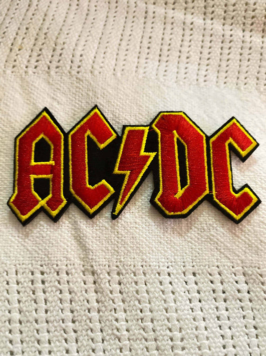 ACDC Logo Patch in red and yellow on white textured fabric background