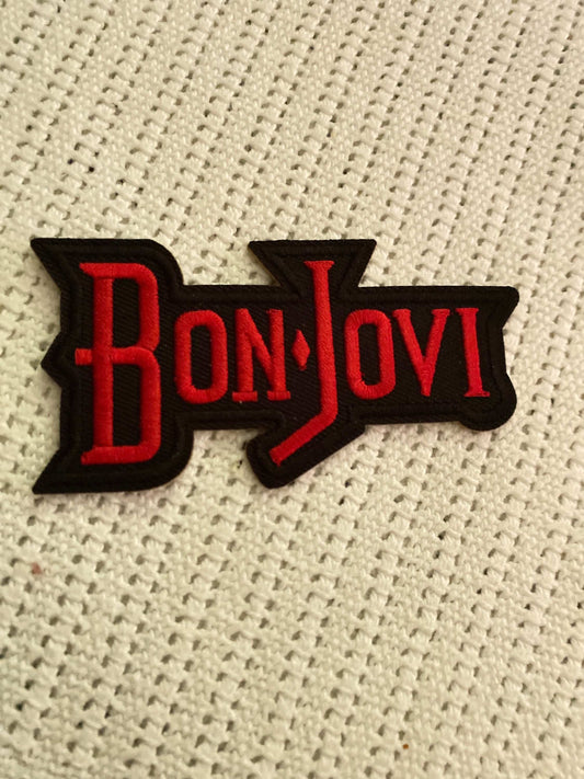 Bon Jovi embroidered patch with red lettering on black background on textured white fabric