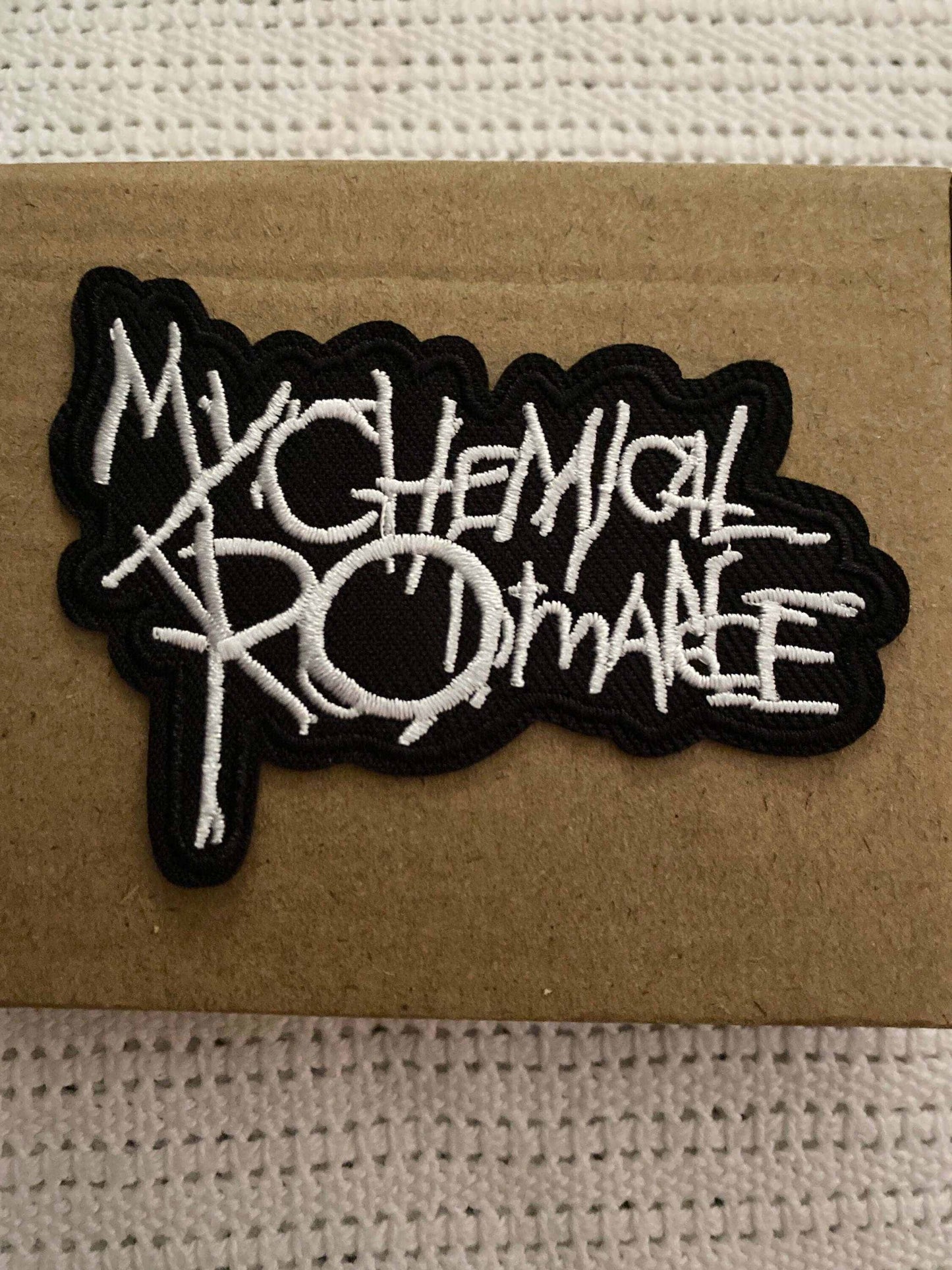 My Chemical Romance embroidered black and white logo patch on a brown background