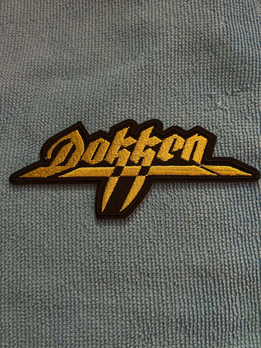 Dokken logo patch with bold yellow lettering on black background for jackets and backpacks