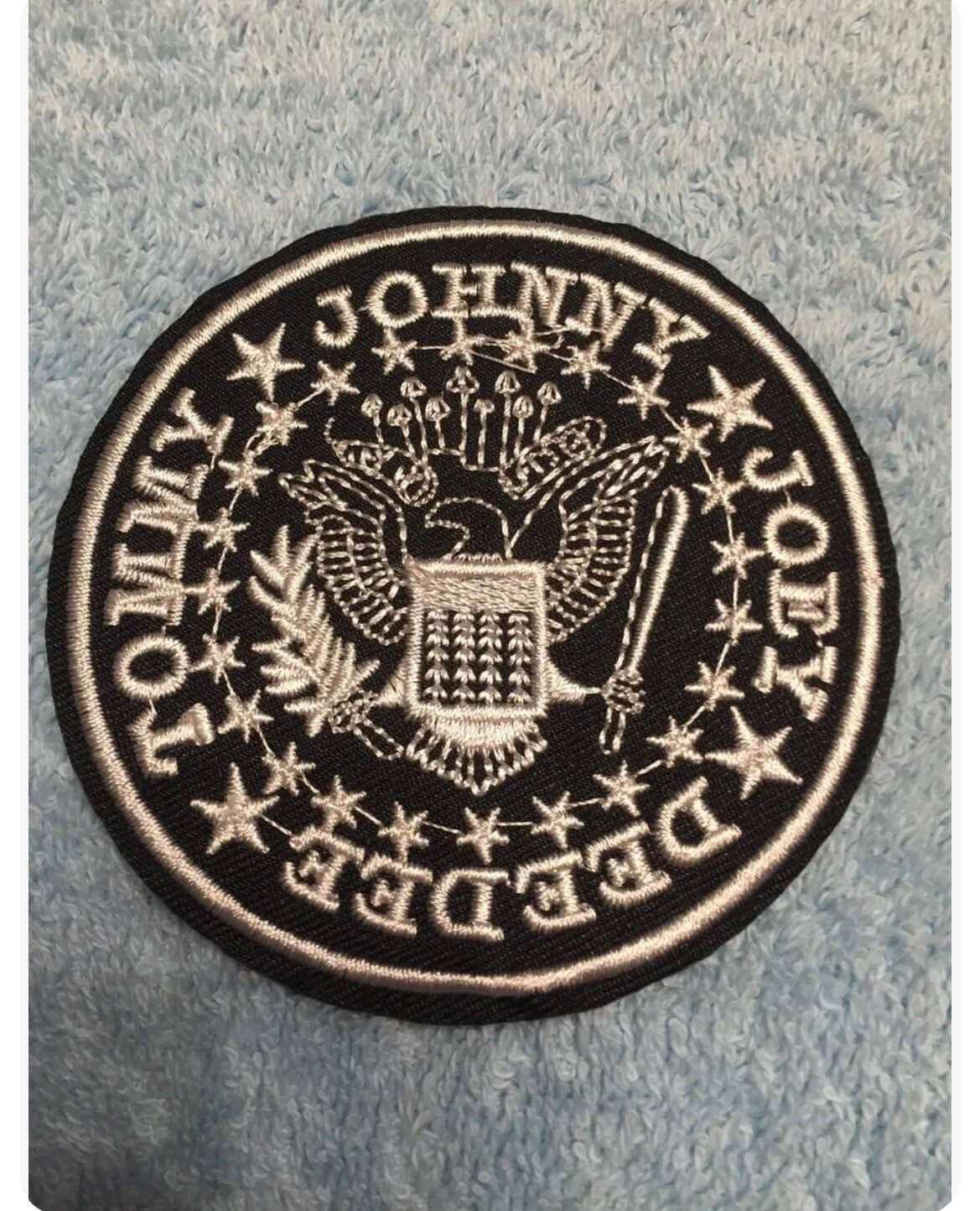 Black and white embroidered Ramones patch featuring band members' names and eagle emblem on fabric background