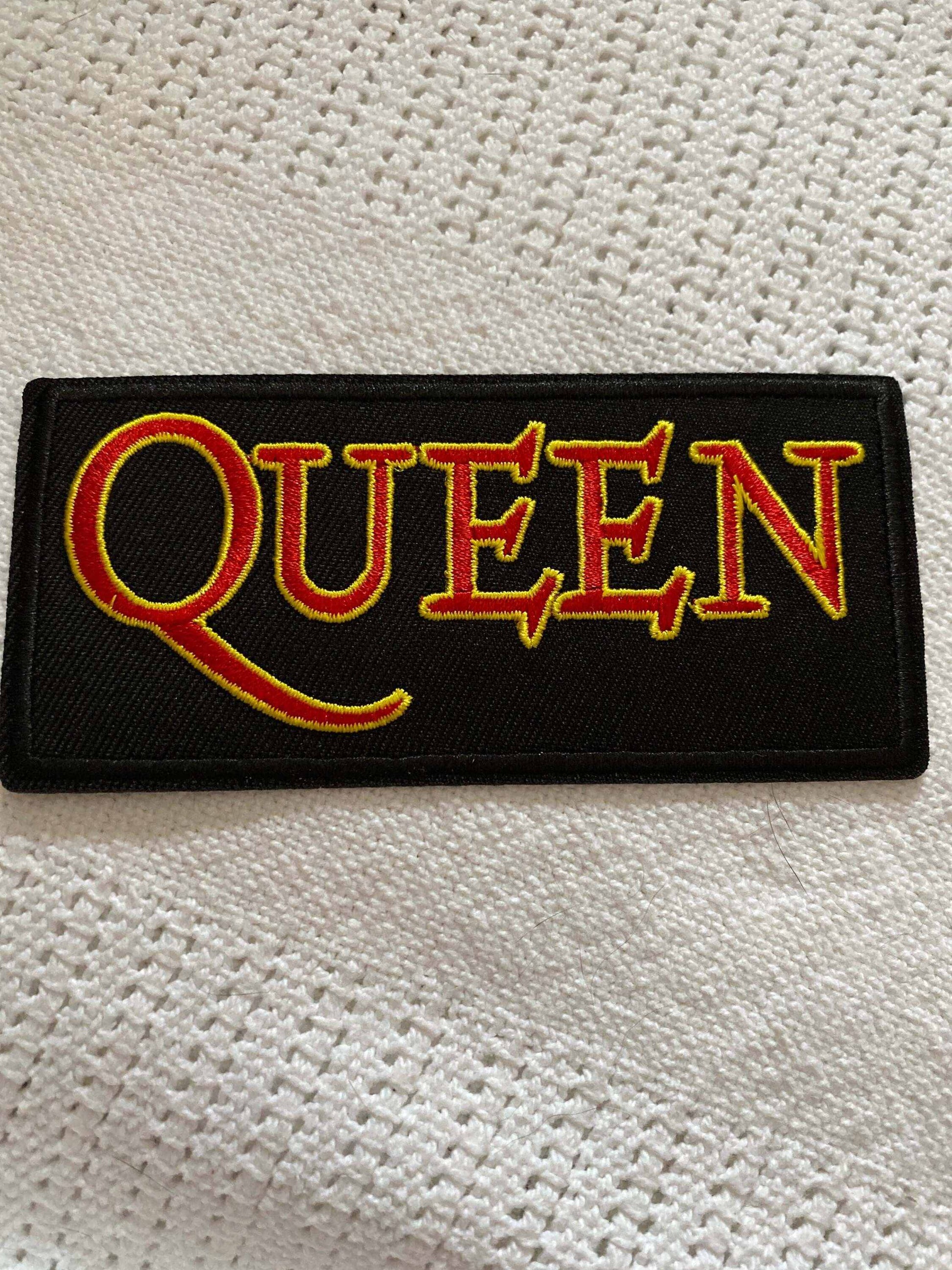 Queen rock band logo patch with bold yellow and red lettering on black background