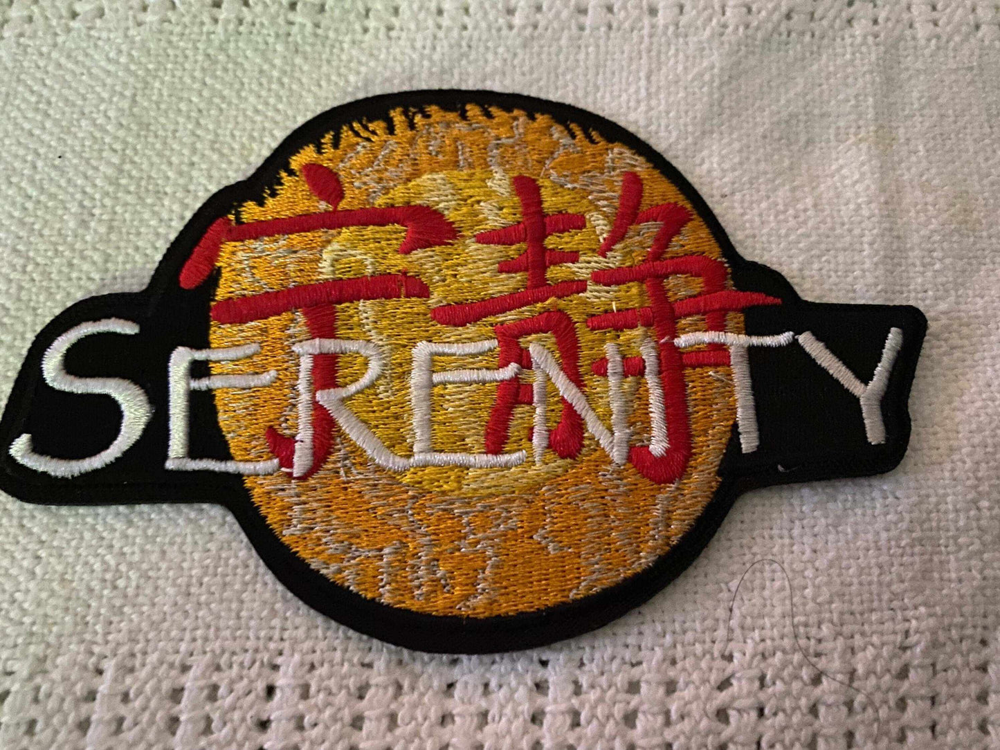 Embroidered Serenity Firefly patch with orange and red design on fabric background