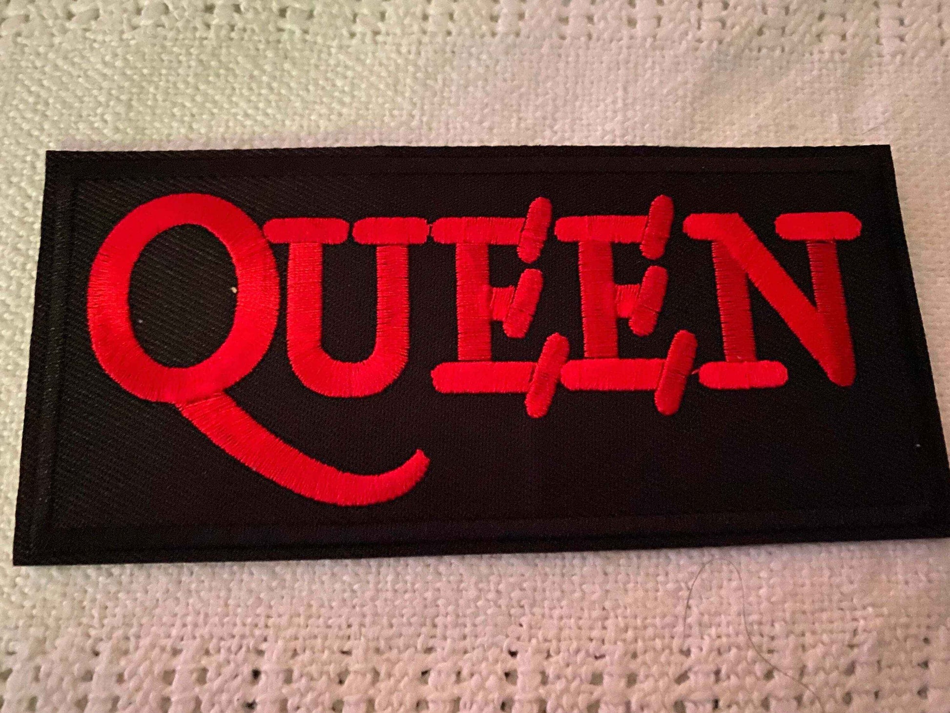 Black fabric patch with bold red embroidered Queen band logo text