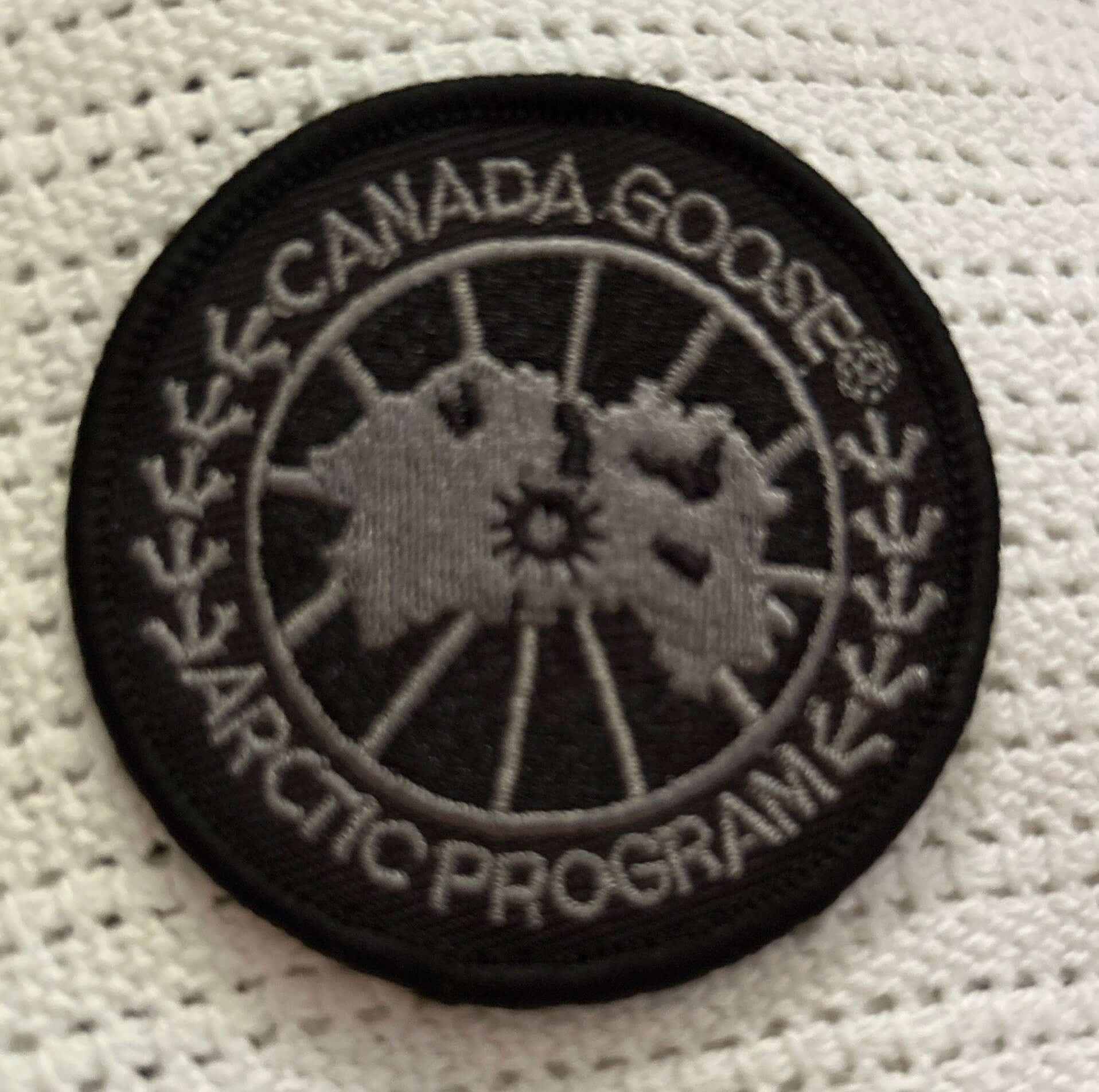 Black and gray Canada Goose Arctic Program circular patch on white fabric background
