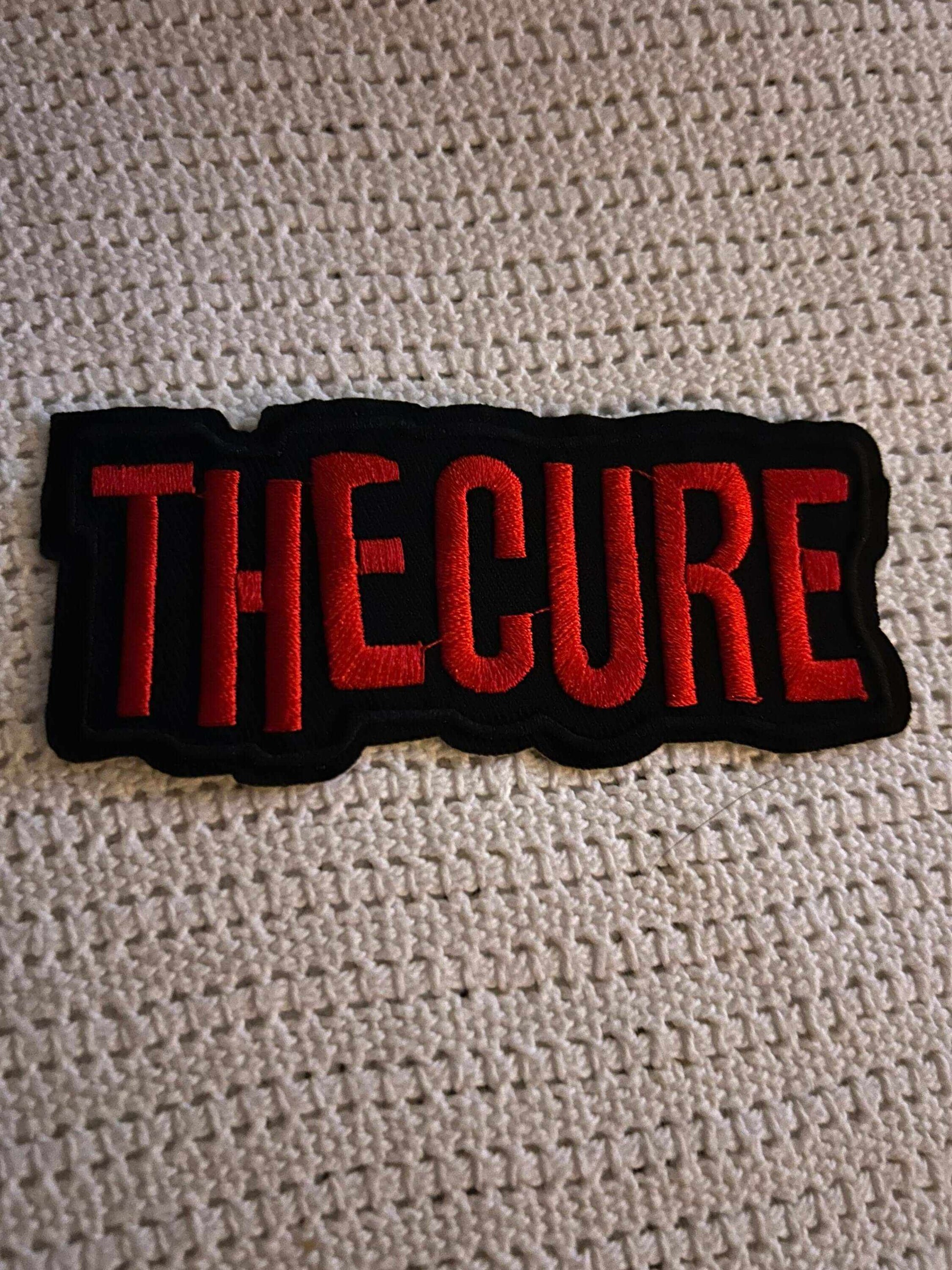 Embroidered TheCure patch with bold red lettering on black background for fans of the English rock band.
